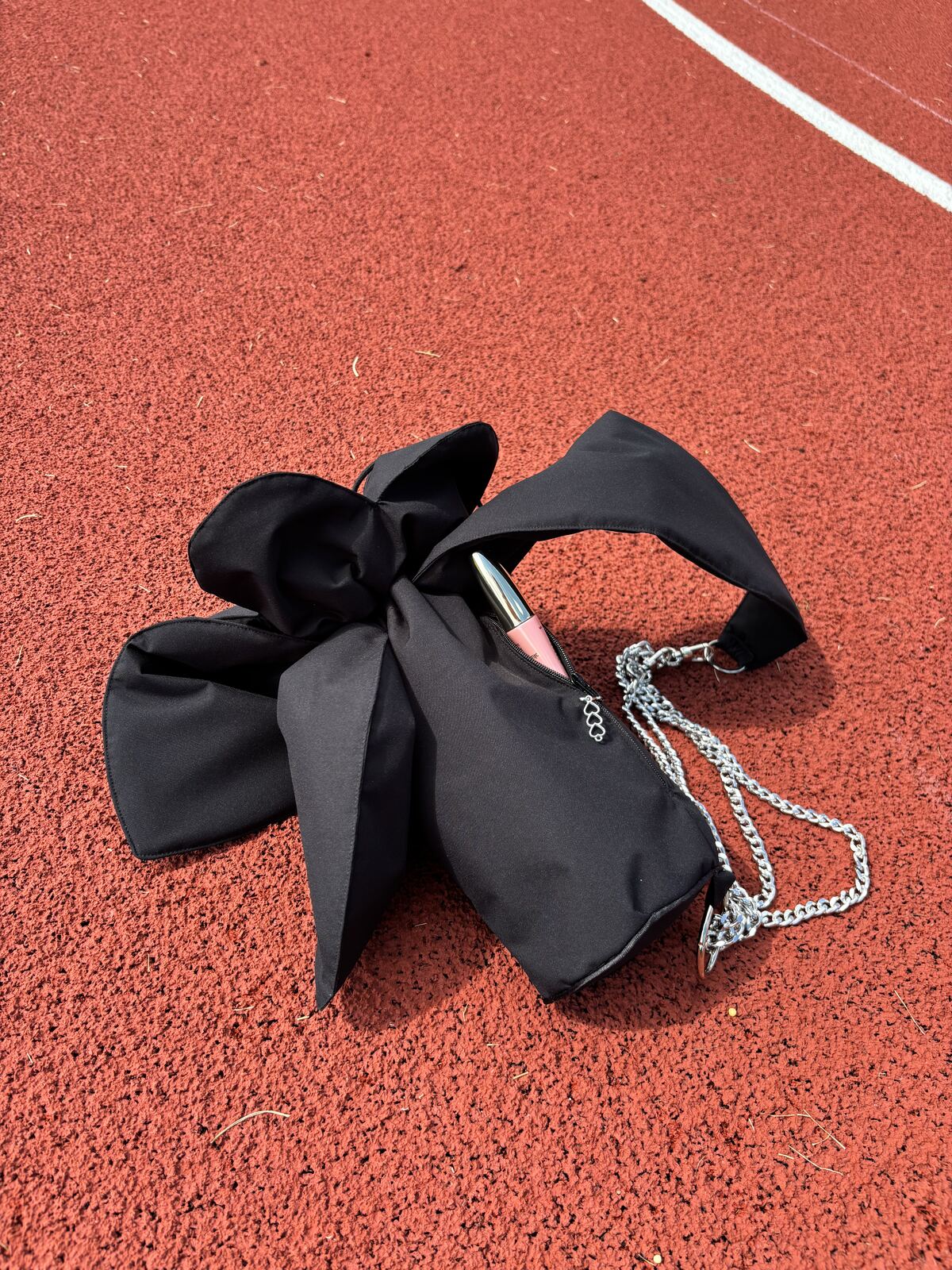 The flower bag and its small top zip pocket, on a running track